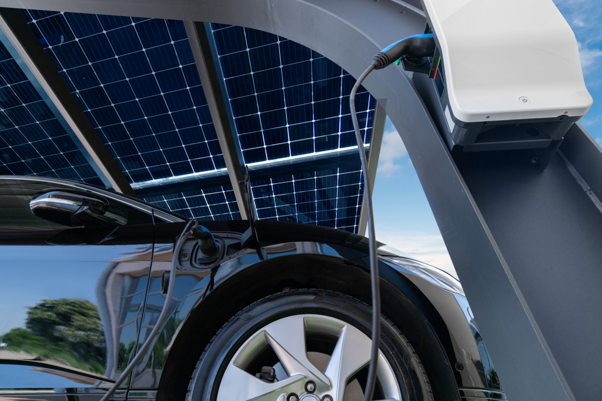 Ladevorgang eines Elektroautos an einer Ladestation unter einem überdachten Solarpanel‑Carport