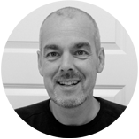 Person in einem schwarzen Shirt vor einer weißen Tür in einem Innenraum